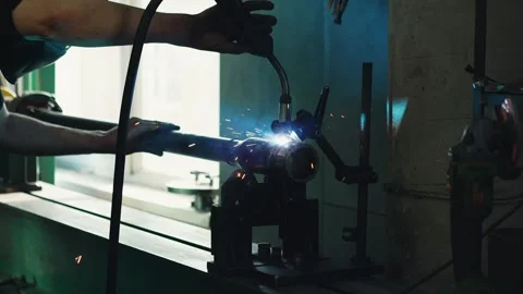 A welder in a protective mask welds a pipe with a welding machine Stock Footage 285641567