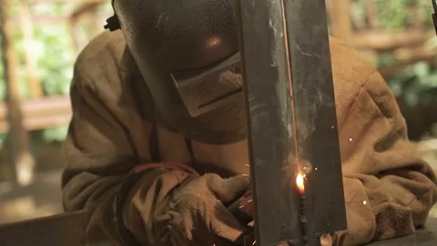 Welder training his dexterity on a piece of metal, at a construction site Stock Footage 255684336