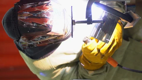 Welder wear work robe, thick protective yellow gloves, welds two metal parts Stock Footage 126358219