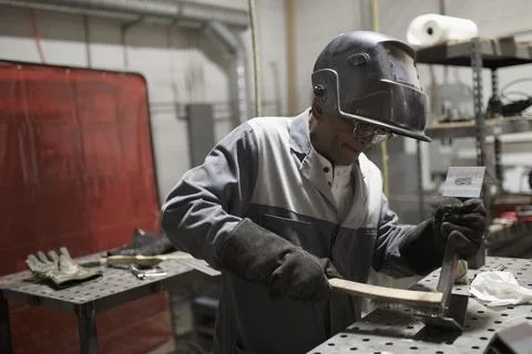 Welder in welding mask working at workbench Stock Photos