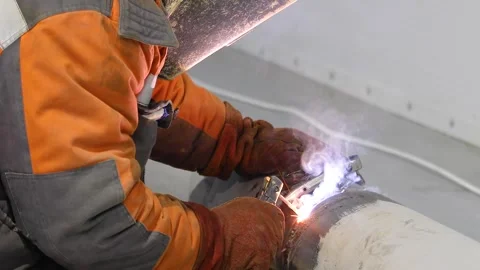 Welder welding a pipe. Welder at a construction site. Construction site. Welding Видео 320021655