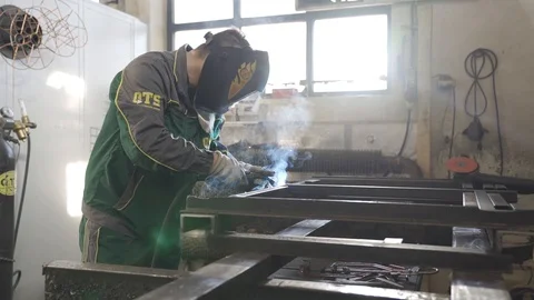 Welder with welding shield welds iron profiles Stock Footage 111706934