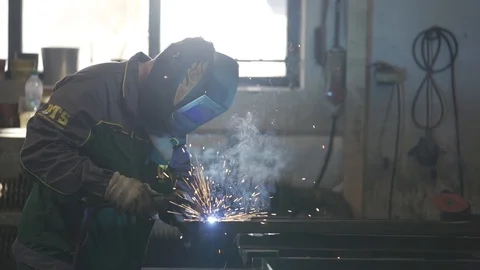 Welder with welding shield welds iron profiles Stock Footage 111707007