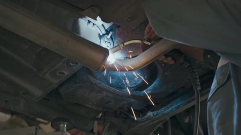 Welder welds exhaust pipe under the bottom of the car closeup Stock Footage 110985035