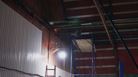 Welder welds a large metal structure in a large hangar Stock Footage 104014308