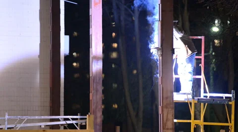Welder welds structural beams on the scaffolding at night Stock Footage 46544012