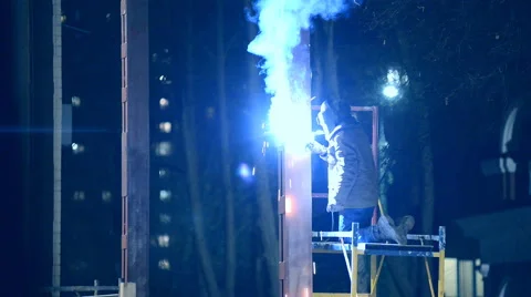 Welder welds structural beams on the scaffolding at night Stock Footage 46694066