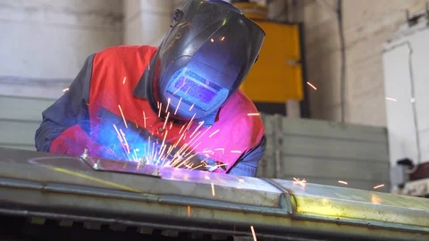 Welder at work, welding metal frame of coal heating boiler, manufacturing boiler Stock Footage 120062424