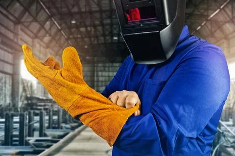 Welder worker pulling on orange gloves close-up view. Stock Photos