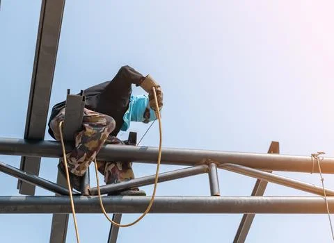 A welder working on a high rooftop. Stock Photos