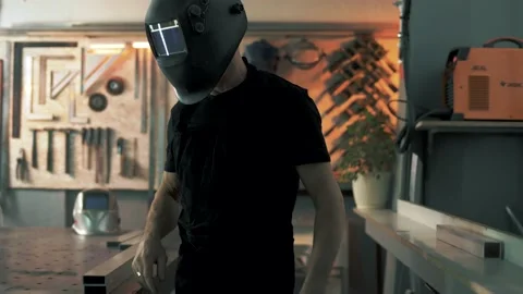 Welding engineer puts on a welding mask and prepares the workplace Stock Footage 179698681