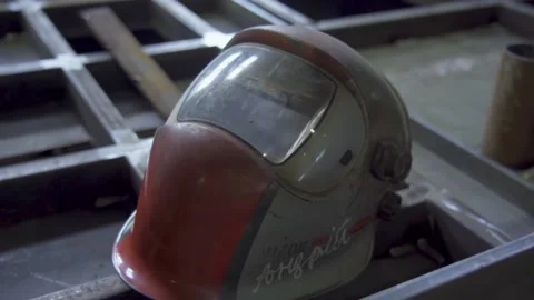 Welding helmet lying on metal surface in industrial workshop Stock Footage 314057289