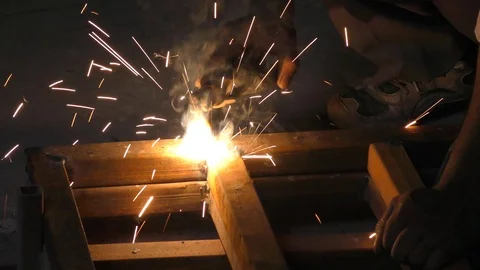 Welding of iron angles and sparkles flying all over with light flash Stock Footage 112853993