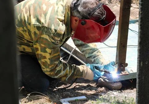 Welding metal by worker in red protective helmet Stock Photos