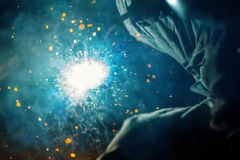 The welding process close-up. Flash of an electric arc and a lot of splashes of Stock Photos