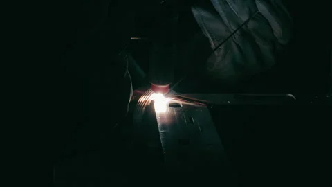 Welding process in a dark industrial workshop. A close-up shot of a welding Stock Footage 284434590