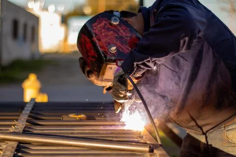 Welding torch welding a grating with a welder helmet Stock Photos