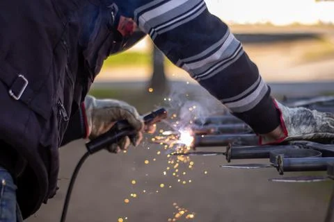 Welding torch welding a grating with a welder helmet Stock Photos