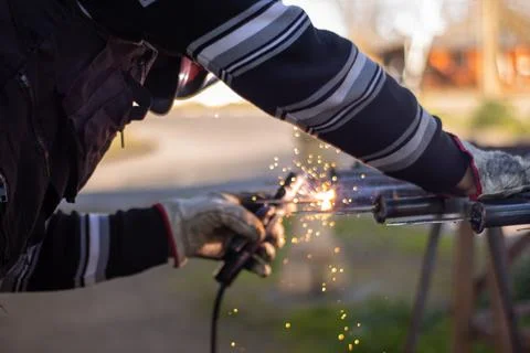 Welding torch welding a grating with a welder helmet Stock Photos