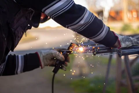 Welding torch welding a grating with a welder helmet Stockfoto's