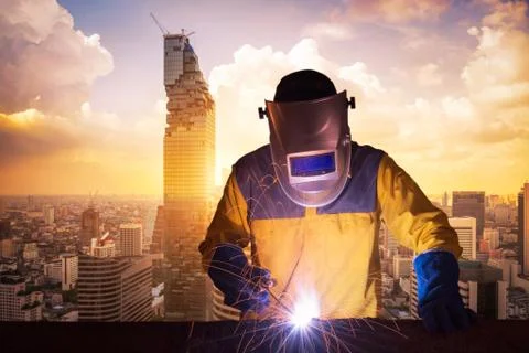 Welding worker welding steel structure with modern building in big city Foto stock