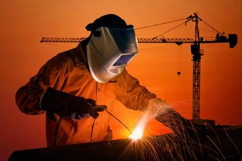 Welding worker welding steel structure with construction crane and building Photos