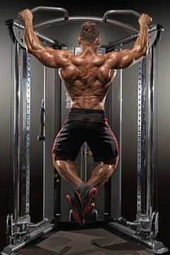Well built man performs pull ups on gym equipment strengthen his back and arms Foto stock