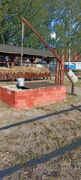 The well with the crane is surrounded by red brickwork. Stock Photos