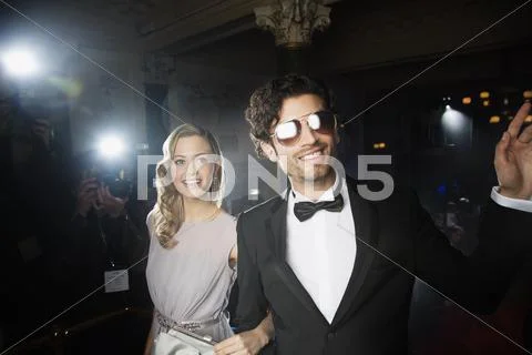 Well dressed celebrity couple waving to paparazzi on red carpet Stock Photos