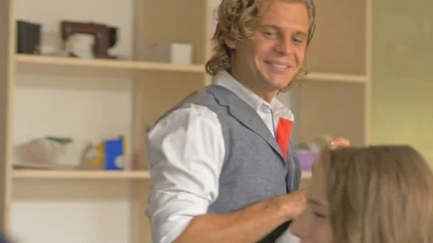 Well-dressed man hanging clothes, laughing with colleagues. Stock-Footage 80469120