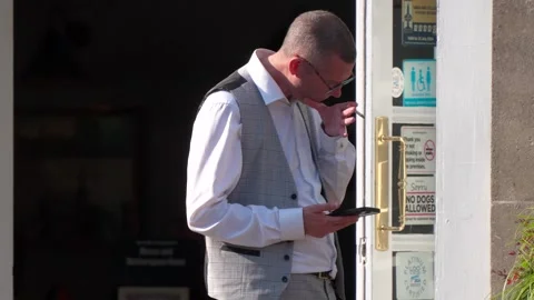 A well dressed man smoking, using his phone and spitting in the street Stock Footage 281066928