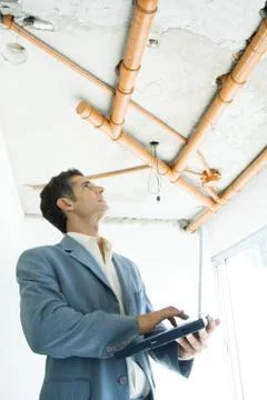 Well-dressed man using laptop, inspecting unfinished home interior 스톡 사진