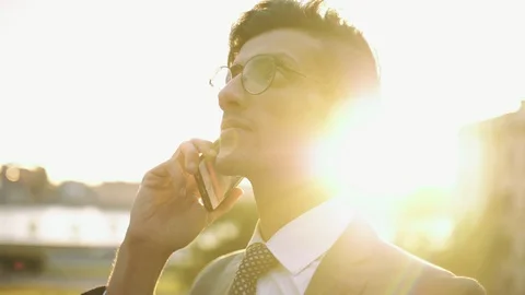 Well-dressed trendy eastern buisnessman in eyeglasses talking with mobile phone Stock Footage 110209768