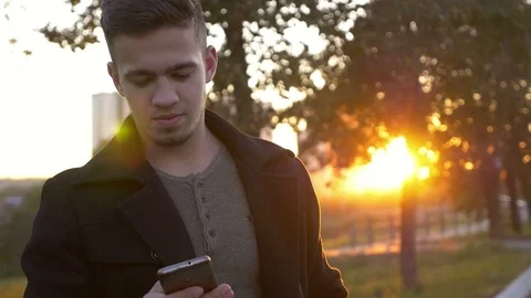 Well-dressed trendy man talking with mobile phone in a city on sunset time Stock Footage 80986143