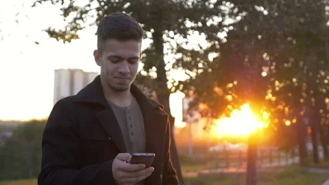 Well-dressed trendy man talking with mobile phone in a city on sunset time Stock Footage 80986767