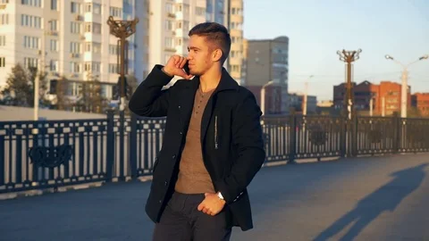 Well-dressed trendy man talking with mobile phone in a city on sunset time Stock Footage 80986863