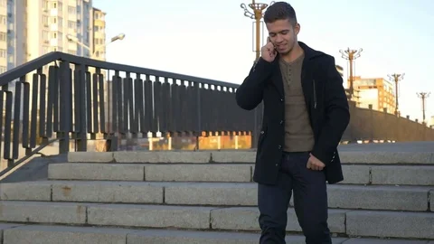 Well-dressed trendy man talking with mobile phone in a city on sunset time Stock Footage 80987339