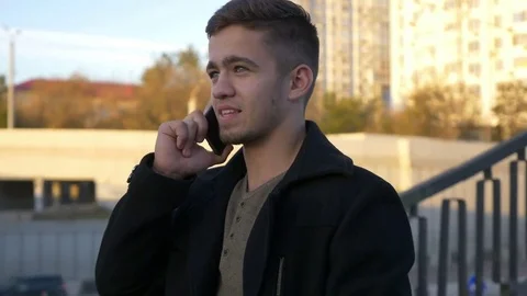 Well-dressed trendy man talking with mobile phone in a city on sunset time Stock Footage 80987362