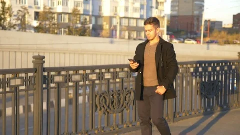 Well-dressed trendy man talking with mobile phone in a city on sunset time Stock Footage 80987502
