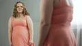 Well-fed girl upset about her mirror reflection, hardly got into favorite dress 4k or 4k+ Resolution
