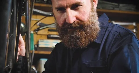 Well-groomed handsome bearded master hipster, specialist in bicycles Stock Footage