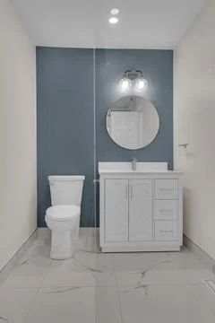 Well lit bathroom with simple decor, toilet, sink, mirror and white cabinets. Stockfoto's
