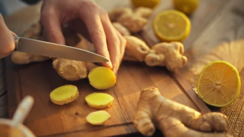 In well-lit kitchen mans hands expertly slice fresh ginger rhizome unleashin Stock Footage 331354160