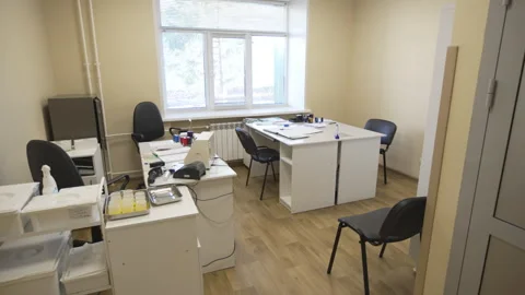 Well-lit office features light tables and dark chairs Stock Footage 312403853