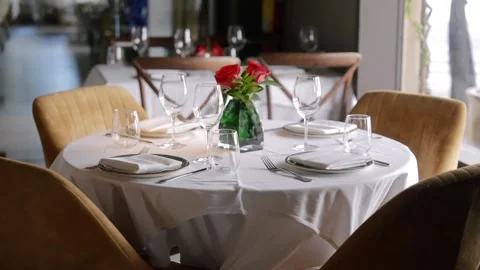 Well-set round table covered with white tablecloth in restaurant. Each place Stock Footage 262265564