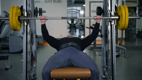 A well-trained athlete rises from under the bar and smiles into the camera 4K Stock-Footage 100257068