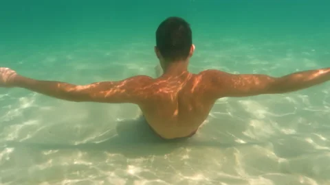 Well trained boy in red trunks under surface in blurry turquoise ocean water Stock Footage 195122717