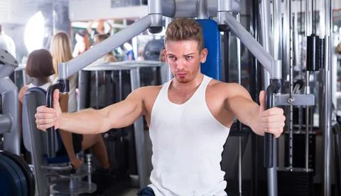 Well trained man using pec deck gym machinery indoors Stock-Fotos