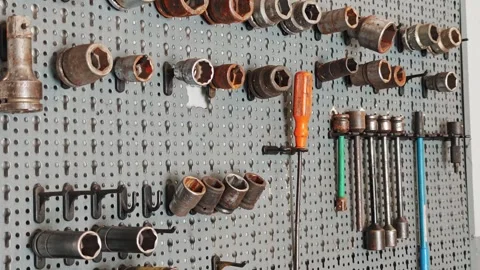 Well Used Socket Wrench Set Hanging on Pegboard Tool Wall at Auto Shop Stock Footage 332827895