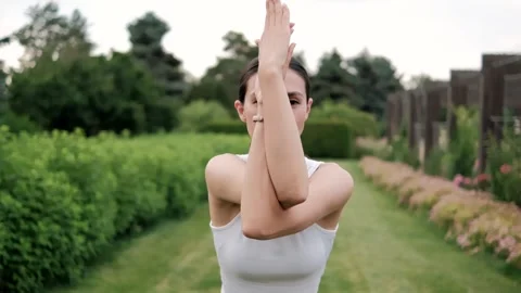 Wellness instructor practicing yoga pose variation in a peaceful garden setting Stock Footage 294896837